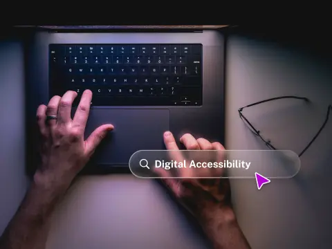 A person's hands are typing on a laptop keyboard, with a search bar displaying 'Digital Accessibility' and glasses nearby.