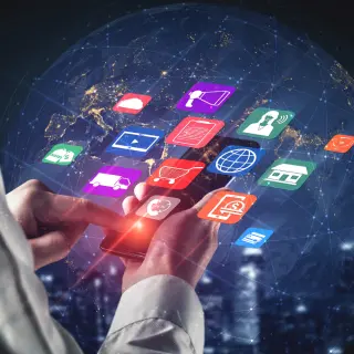 A person holds a smartphone displaying various colorful app icons against a digital globe background, symbolizing connectivity and technology.