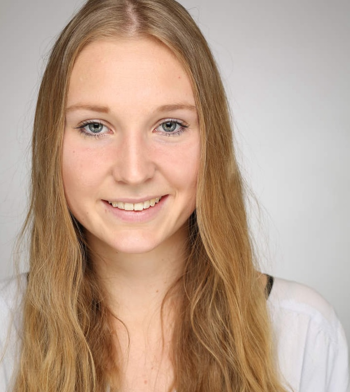 A young woman with long, straight blonde hair smiles warmly at the camera against a neutral background.