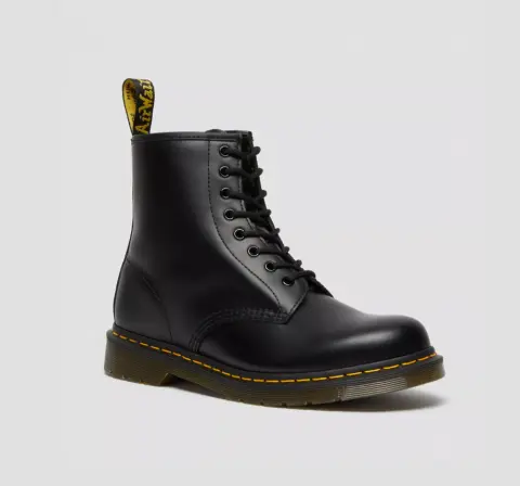 A black leather ankle boot with laces and a yellow stitching detail, featuring a pull tab at the back.