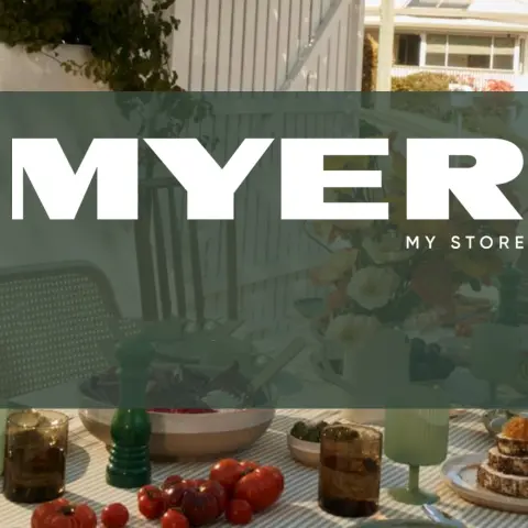 A beautifully set outdoor dining table with various dishes, drinks, and flowers, featuring the Myer logo prominently displayed.