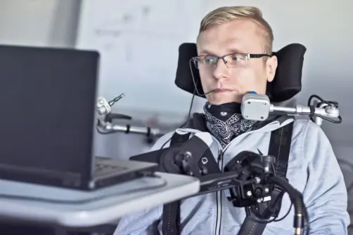 Disabled student in class room working with laptop.